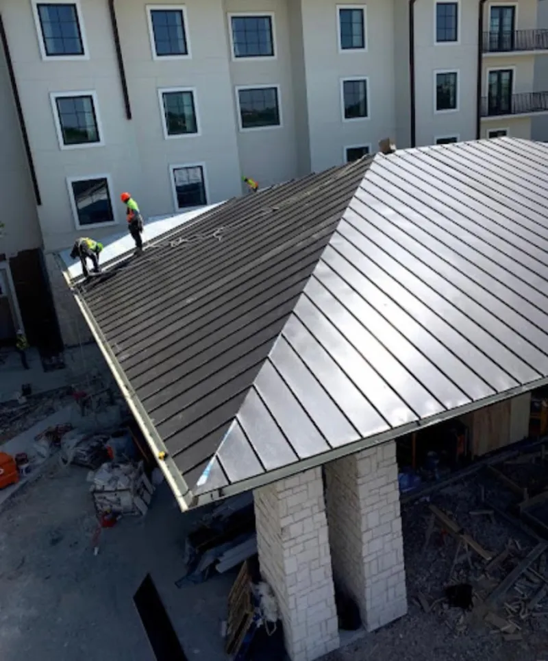 Crew installing standing seam metal roof panels on a commercial project in Dracut